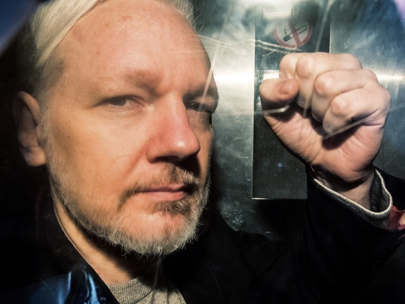 WikiLeaks founder Julian Assange gesturing from the window of a prison van as he is driven into Southwark Crown Court in London