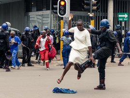 An anti-riot police man in Zimbabwe tackles a woman with his boot as they dispersed a crowd gathered to hear an address by leader of the MDC