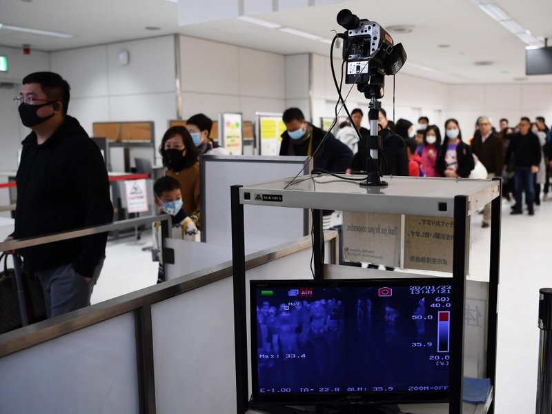 Passengers who arrived on one of the last flights from the Chinese city of Wuhan walk through a health screening station at Narita airport in Chiba prefecture, outside Tokyo, on January 23, 2020, as countries screen for anyone showing symptoms of a SARS-l