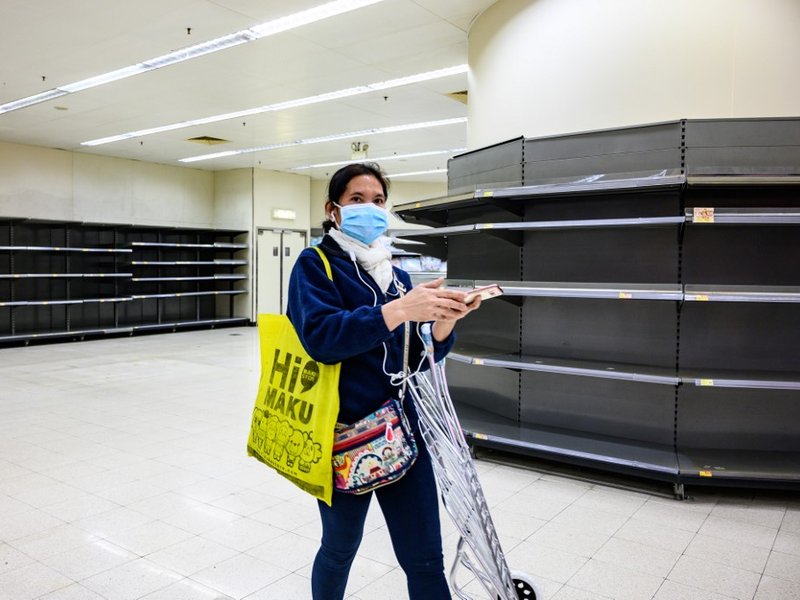 A shopper wearing a protective facemask walks past bare supermarket shelves, usually stocked with toilet paper and kitchen rolls, in Hong Kong on February 6, 2020. Panic buyers in Hong Kong have descended on supermarkets to snap up toilet paper after fals