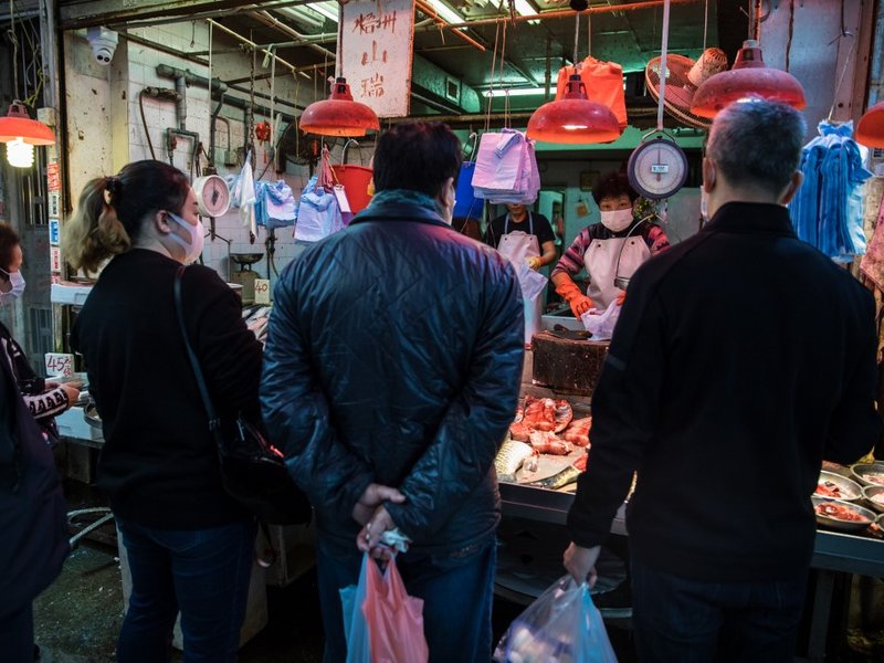 A fish monger wearing a protective face mask prepares an order for a customer at a fresh food market in Hong Kong on February 9, 2020, as a preventative measure after a coronavirus outbreak which began in the Chinese city of Wuhan. The previously unknown