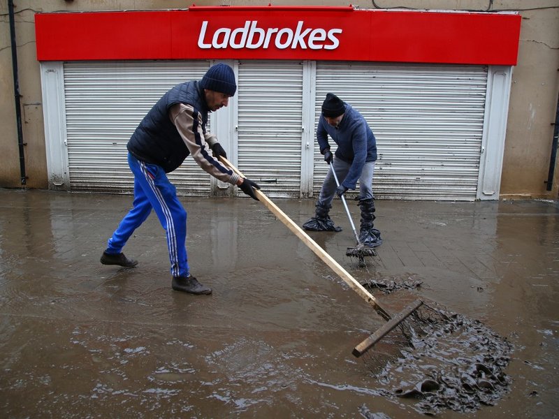 Men clean up mud from the street in Pontypridd in south Wales on February 16, 2020, as Storm Dennis causes flooding across large swathes of Britain. As Storm Dennis sweeps in, the country is bracing itself for widespread weather disruption for the second