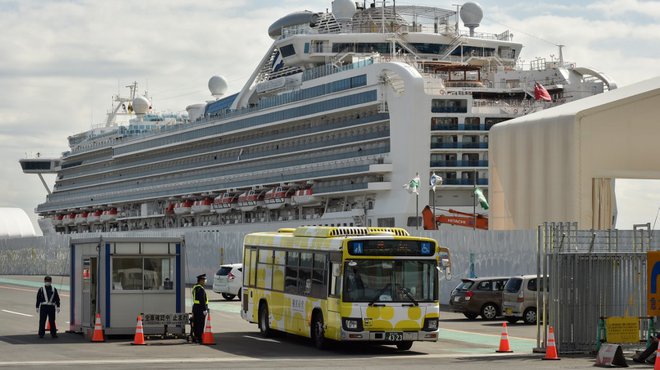 A bus carrying passengers who disembarked from the Diamond Princess cruise ship (back) in quarantine due to fears of the new COVID-19 coronavirus, leaves the Daikoku Pier Cruise Terminal in Yokohama on February 19, 2020. Relieved passengers began leaving