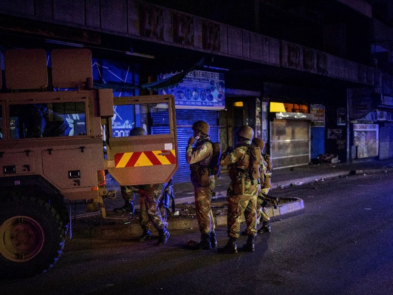 Members of the South African National Defence Force (SANDF) climb on an Armoured Personal Carrier (APC) during an operation in the Johannesburg CBD, on March 27, 2020. South Africa came under a nationwide military-patrolled lockdown on March 27, 2020, joi