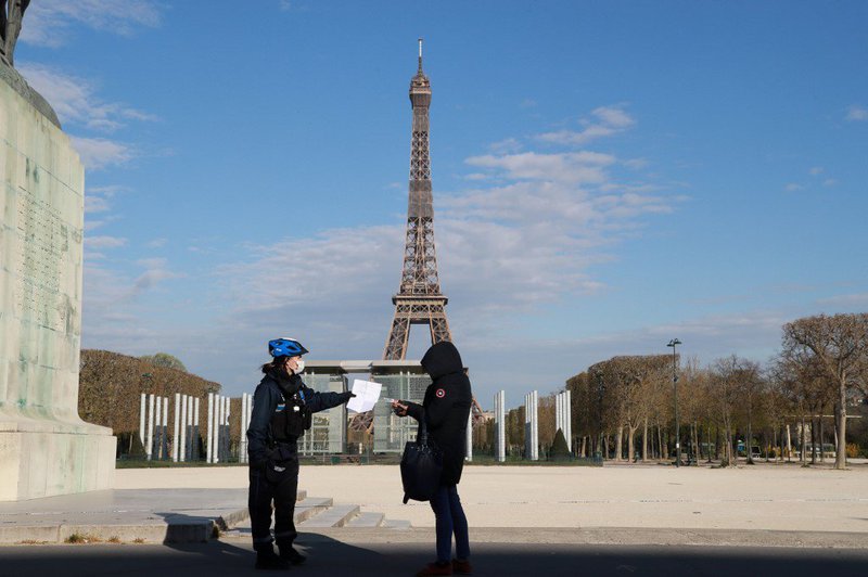 A French police officer control the outings authorisation of a person near Champs de Mars in Paris, on April 6, 2020, on the twenty-first day of a strict lockdown in France to stop the spread of COVID-19, caused by the novel coronavirus.