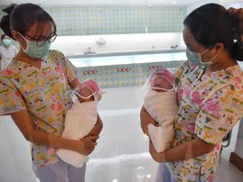 This photo taken through a glass window at a maternity ward shows nurses holding newborn babies wearing face shields, in an effort to halt the spread of the COVID-19 coronavirus, at Praram 9 Hospital in Bangkok on April 9, 2020.