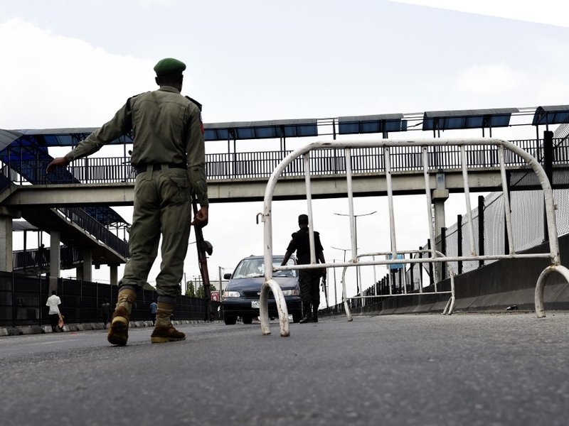 A Nigerian police officer flags down an on coming vehicle at a checkpoint to enforce the extended lockdown as part of measures to prevent the spread of COVID-19 Coronavirus in Lagos, on April 12, 2020. Christians observed the traditional Easter services i