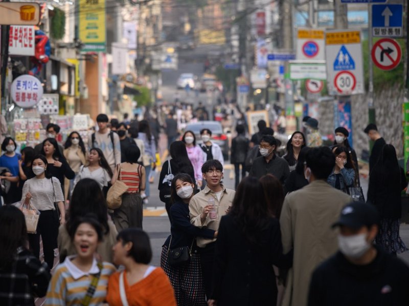 In a photo taken on May 10, 2020, people wearing face masks walk along a street in the Hongdae district of Seoul. South Korea announced its highest number of new coronavirus cases for more than a month on May 11, driven by an infection cluster in a Seoul