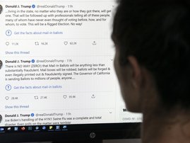This illustration photo shows an editor in Los Angeles looking at the official Twitter account of US President Donald Trump on May 26, 2020, with two tweets by the president under which Twitter posted a link reading "Get the facts about mail-in ballots".