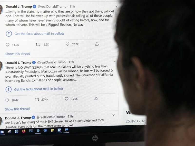This illustration photo shows an editor in Los Angeles looking at the official Twitter account of US President Donald Trump on May 26, 2020, with two tweets by the president under which Twitter posted a link reading "Get the facts about mail-in ballots".