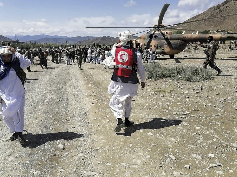 This photograph taken on June 22, 2022 and received as a courtesy of the Afghan government-run Bakhtar News Agency shows soldiers and Afghan Red Crescent Society officials near a helicopter at an earthquake hit area in Afghanistan's Gayan district, Paktik