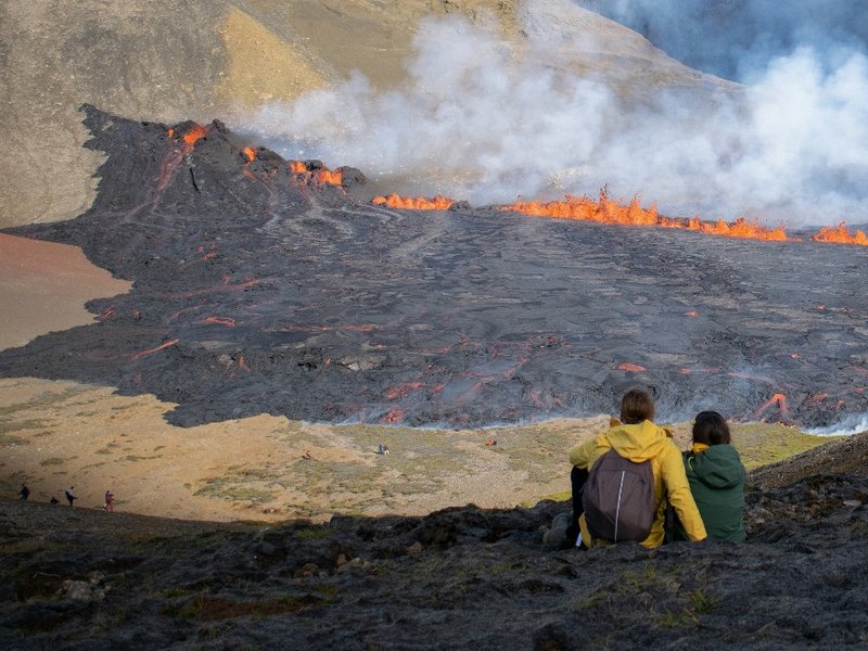 People look at the lava flowing at the scene of the newly erupted volcano at Grindavik, Iceland on August 3, 2022.  A volcano erupted on August 3, 2022 in Iceland in a fissure near Reykjavik, the Icelandic Meteorological Office (IMO) said as lava could be