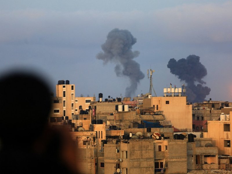 A Palestinian boy watches smoke billowing from targets during Israeli airstrikes on the southern Gaza region of Khan Yunis, controlled by the Hamas movement, on May 11, 2021. Israel launched deadly air strikes on Gaza in response to a barrage of rockets f