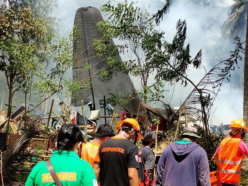 In this handout photo taken on July 4, 2021 and received from the Philippine military Joint Task Force-Sulu (JTF-Sulu), rescue workers arrive as smoke billows from the wreckage of a Philippine Airforce C-130 transport plane after it crashed near the airpo
