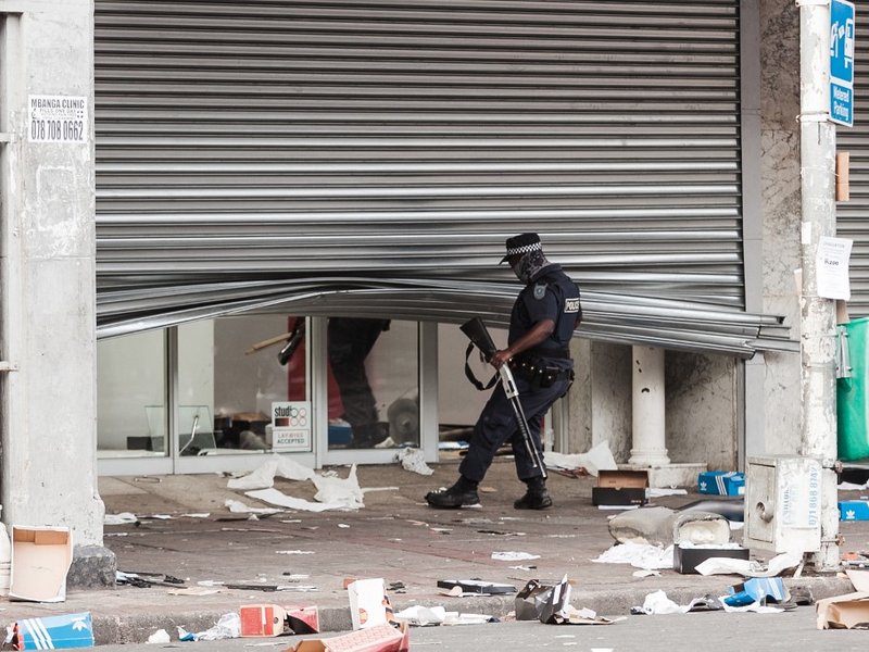 A member of the Durban Metro Police looks at a looted retail store in central Durban, on July 11, 2021. Several shops are damaged and cars burnt in Durban, following a night of violence. Police are on the scene trying to control further protests. It is un