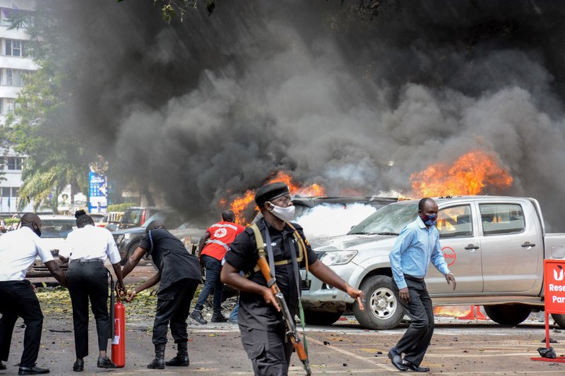 People extinguish fire on cars caused by a bomb explosion near Parliament building in Kampala, Uganda, on November 16, 2021. Two explosions hit Uganda's capital Kampala on November 16, 2021, injuring a number of people in what police termed an attack on t