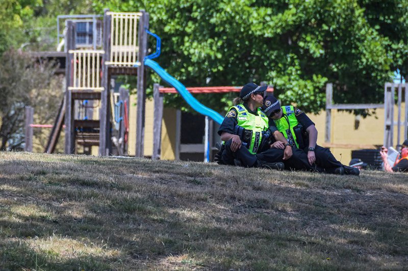 This photo taken and provided on December 17, 2021 by The Advocate/ACM shows members of the local police reacting near a playground outside the Hillcrest Primary School the day after five children died and four others were injured when a bouncy castle was