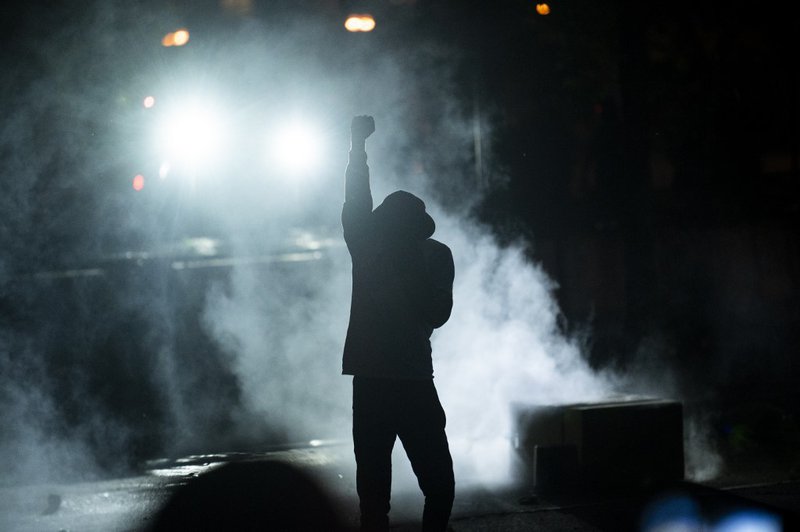 A protester holds up a fist in a cloud of tear gas outside the Third Police Precinct building on May 28, 2020 in Minneapolis, Minnesota. Police and protesters continued to clash for a third night after George Floyd was killed in police custody on Monday.