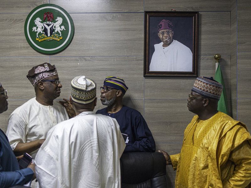 Members of the All Progressives Congress (APC) party discuss as they stand under a portrait of party's presidential candidate Bola Ahmed Tinubu during a press conference at the party's campaign headquarters in Abuja on February 27, 2023. Nigeria slowly co