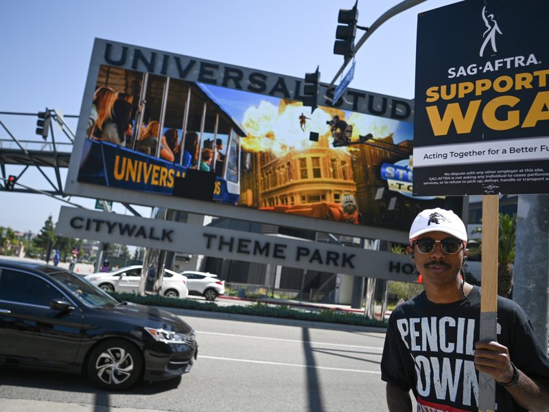 A supporter holds a "SAG AFTRA Supports WGA" sign on the Hollywood writers picket line outside Universal Studios Hollywood in Los Angeles, California, June 30, 2023.