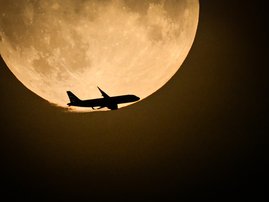 A British Airways Airbus A320 from Belfast and preparing to land at Heathrow, flies past the full moon rising in the skye of London, on August 30, 2023.