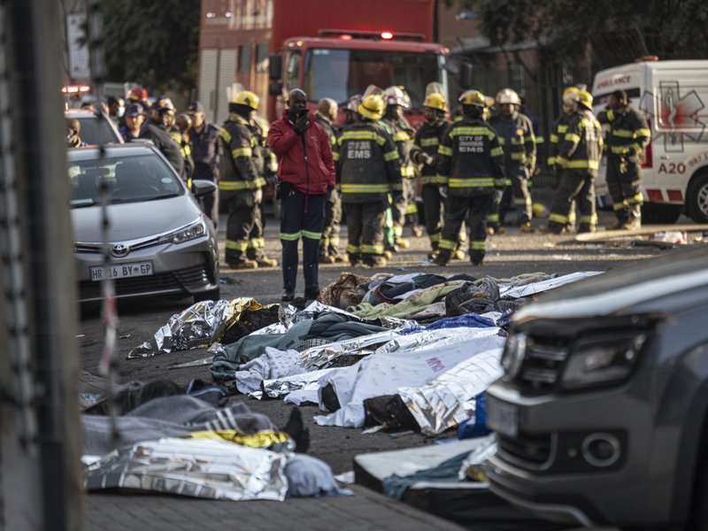 Bodies covered in blankets and sheets are seen at the scene of a fire in Johannesburg