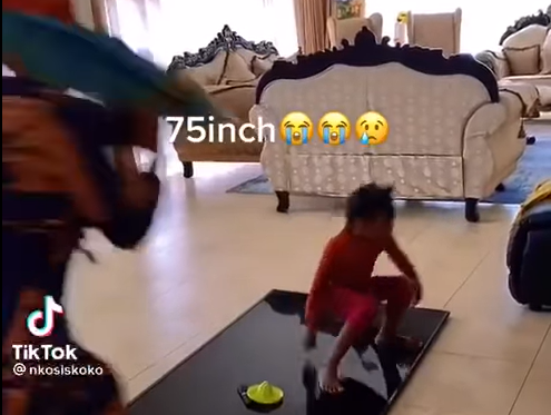 kid playing on top of 75inch tv
