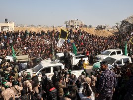 TOPSHOT - Crowds gather as Palestinian Hamas and Islamic Jihad fighters arrive near the family home of slain Hamas leader Yahya Sinwar, where the Hamas militant group prepares to hand over Israeli and Thai hostages to a Red Cross team in Khan Yunis