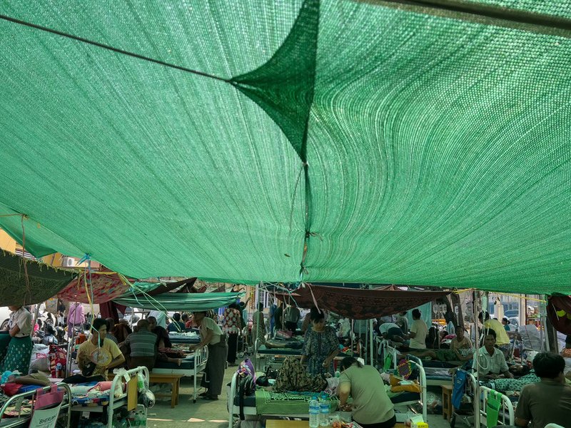 Patients lie on beds in the compound of Mandalay General Hospital in Mandalay