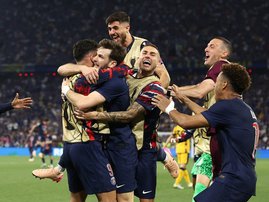 Paris Saint Germain forward Khvicha Kvaratskhelia is embraced by teammates after scoring a fourth goal for PSG during the UEFA Champions League final
