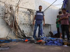 Palestinian children and a journalist check the destroyed Al Jazeera tent at Al-Shifa Hospital in Gaza City