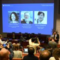 Nobel Committee Secretary General Thomas Perlmann (R) addresses journalists in front of a screen displaying the portraits of (L-R) Mary E Brunkow, Fred Ramsdell and Shimon Sakaguchi during a press conference where the winners of the 2025 Nobel Prize in Ph
