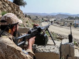 A Taliban security personnel stands guard along a road near the Ghulam Khan zero-point border crossing between Afghanistan and Pakistan