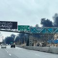 Vehicles move along a highway near plumes of black smoke billowing, in Tehran