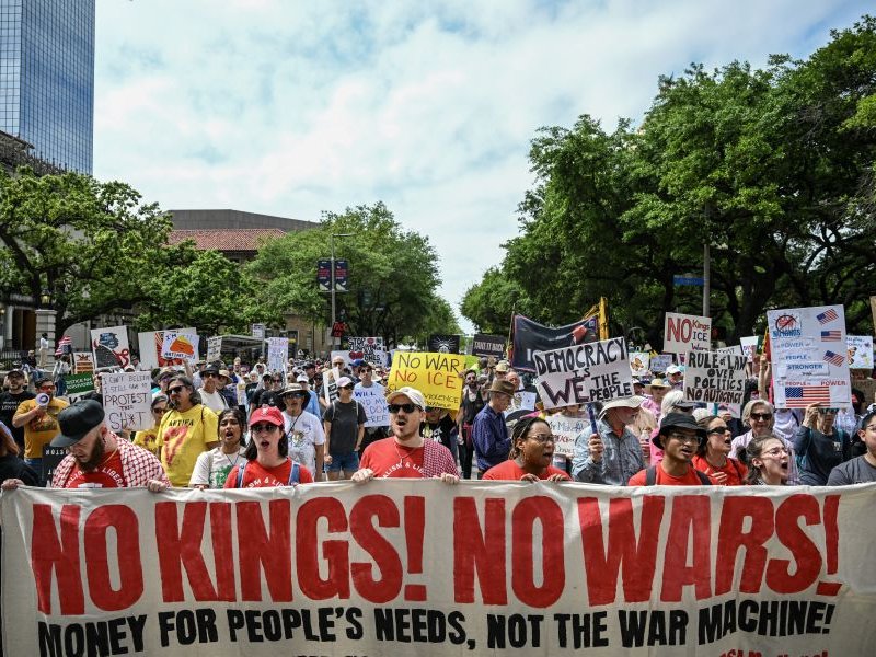 People holding signs march downtown during the "No Kings" national day of protest in Houston on March 28, 2026.