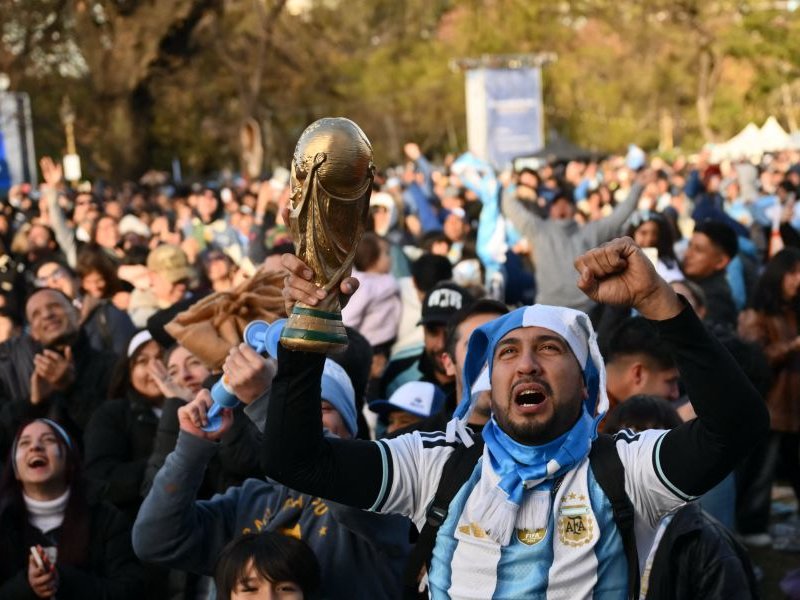 An Argentina fan celebrates a goal scored by Argentina’s forward Lionel Messi while raising a replica of the FIFA World Cup trophy as they watch the 2026 FIFA World Cup