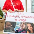 A woman carries a sign to show support for the three murdered children of Lindsay Clancy