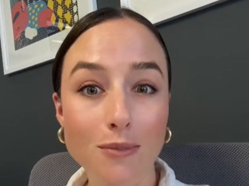 A Caucasian woman with her hair tied back and hoop earrings