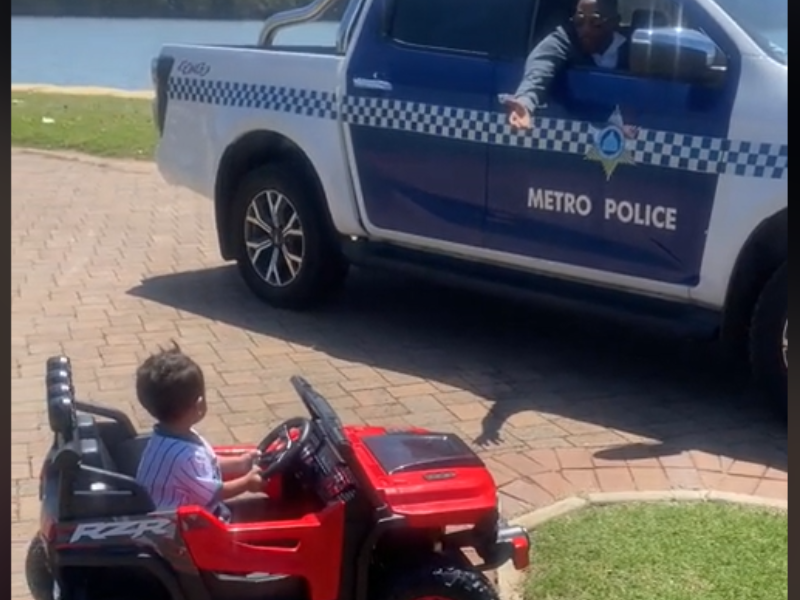 A Durban policeman talks to a little boy on a mini ride on car
