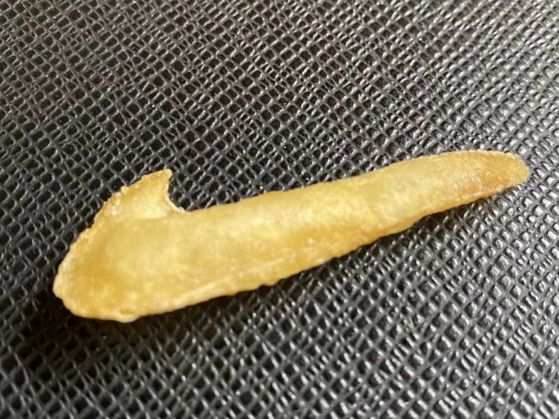 A French Fry shaped like a tick on a black surface
