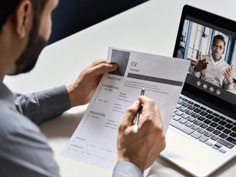 A HR recruiter or employer holds a CV whilst conducting an online interview with applicant