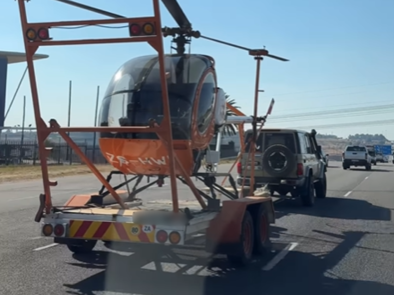 A Land Cruiser towing a helicopter on the freeway