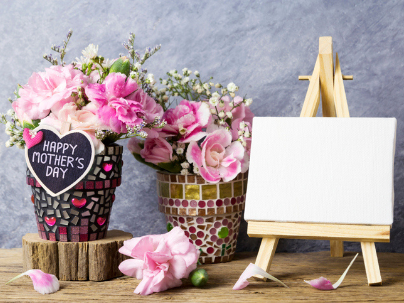A Mothers Day message on wood with a heart and pink flowers in a pot