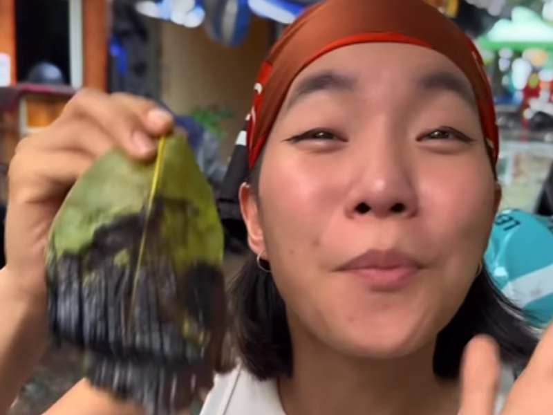 A Vietnamese woman holds a leaf dessert in her hand