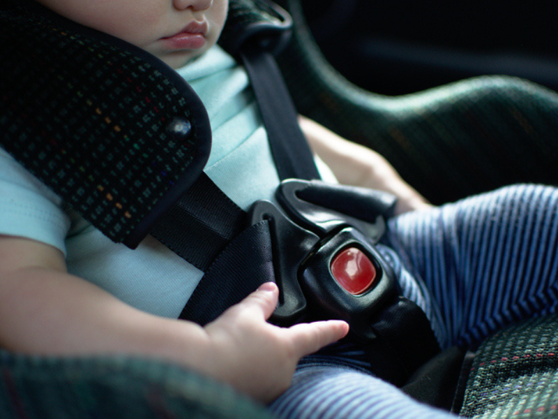 A baby sitting in a rear facing seat with safety belt on