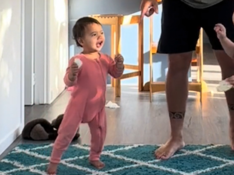 A baby waking towards her sister
