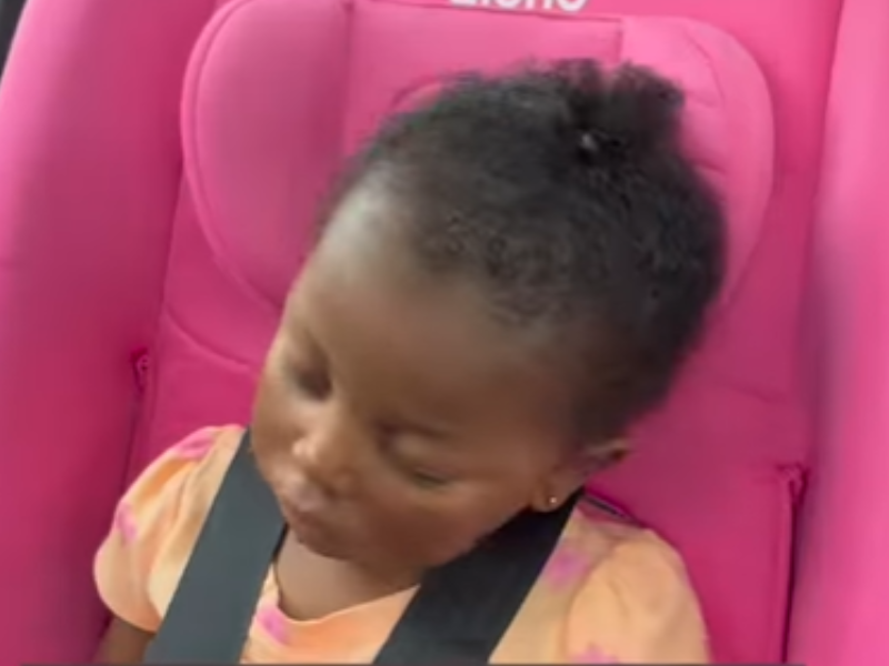A baby's head falls as she sleeps on her car seat
