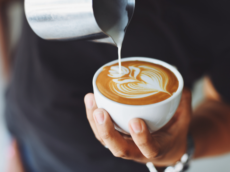 A barista serving up some coffee with artistic flower design