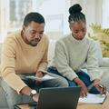 A black couple working on their budget on a laptop