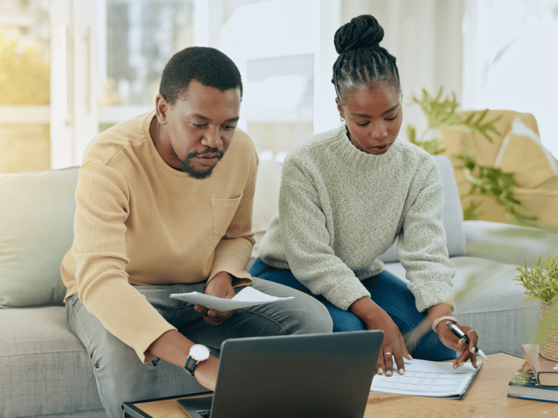 A black couple working on their budget on a laptop